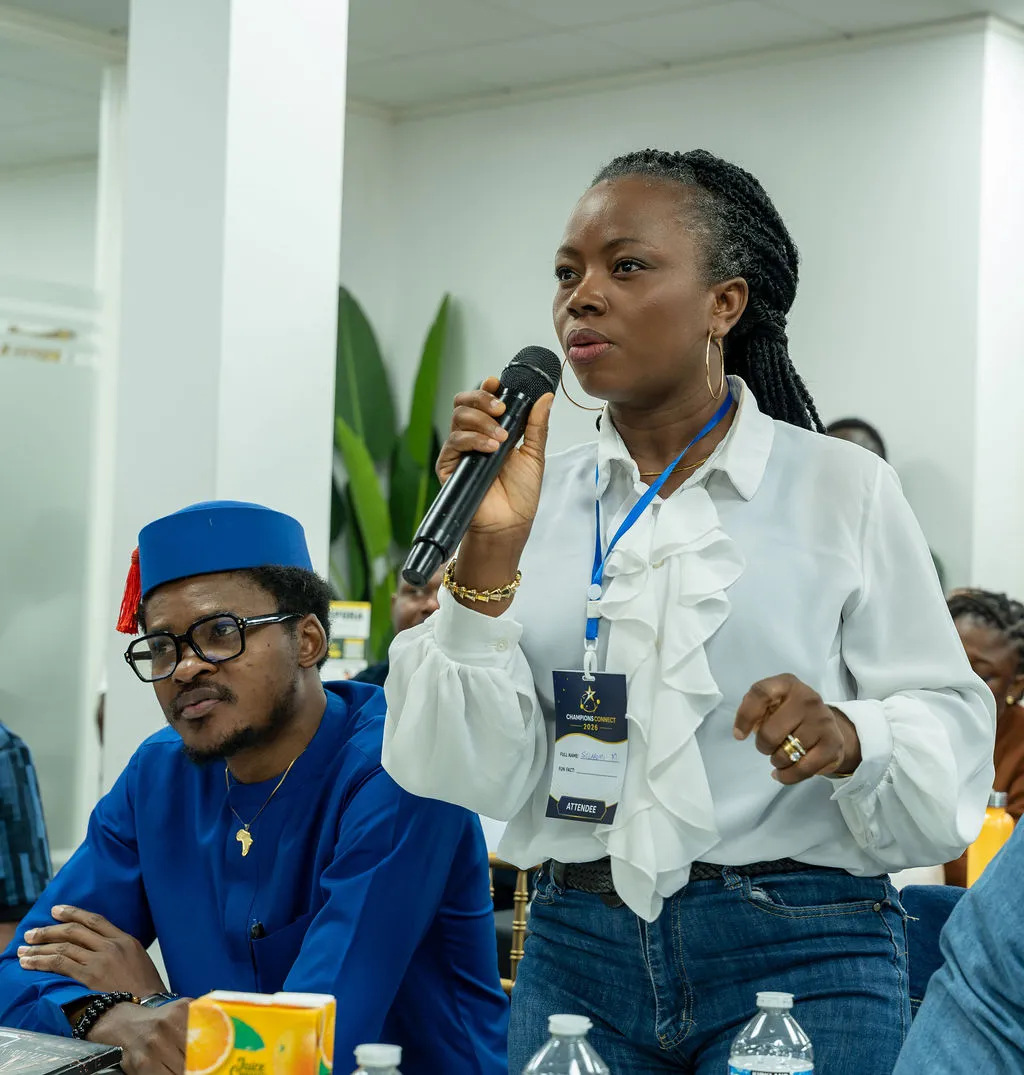 An attendee standing to ask a question into a microphone while a neighbour listens