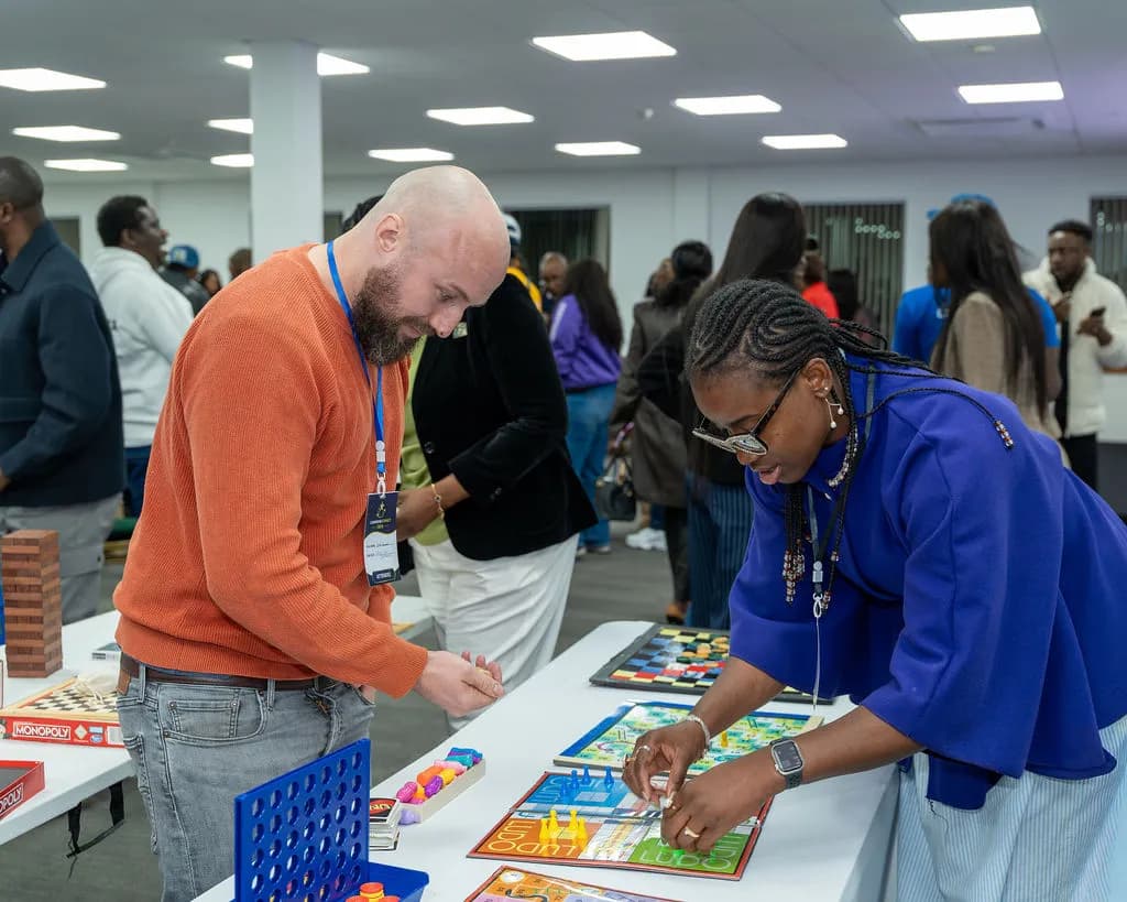 Two attendees playing board games at a games table with Monopoly, Ludo and Connect 4