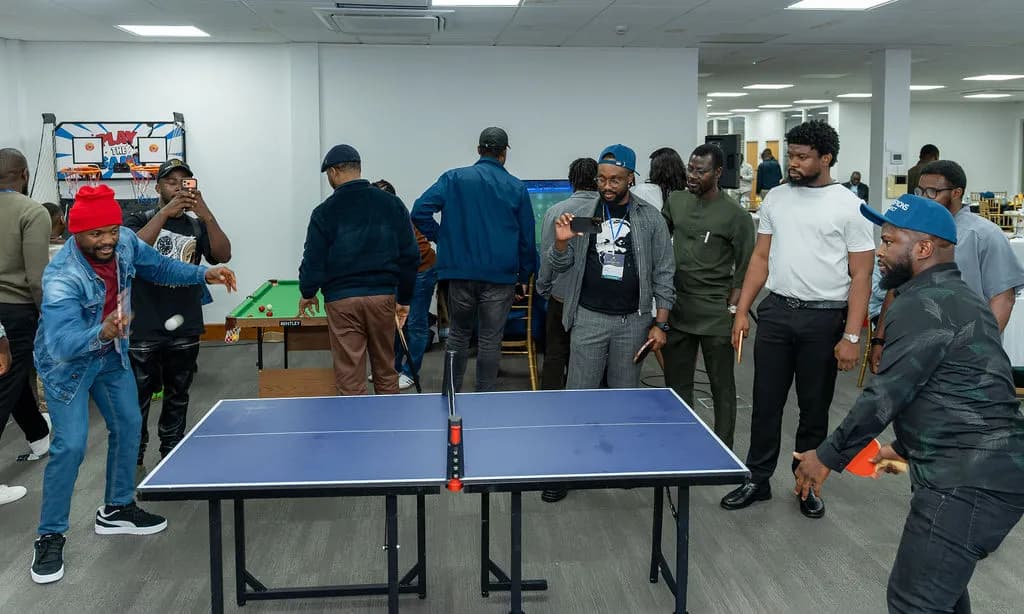 Attendees playing table tennis while others cheer and film on their phones