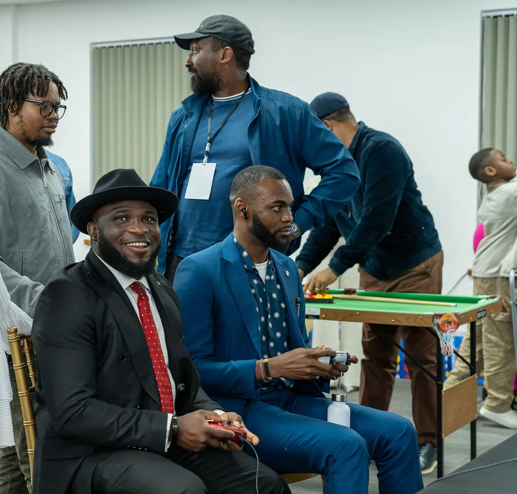 Attendees playing a console game and smiling, with a pool table behind them