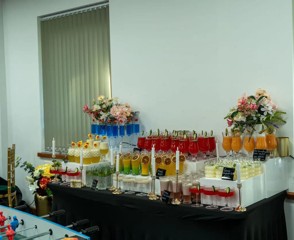 A refreshment table with colourful drinks and flower arrangements